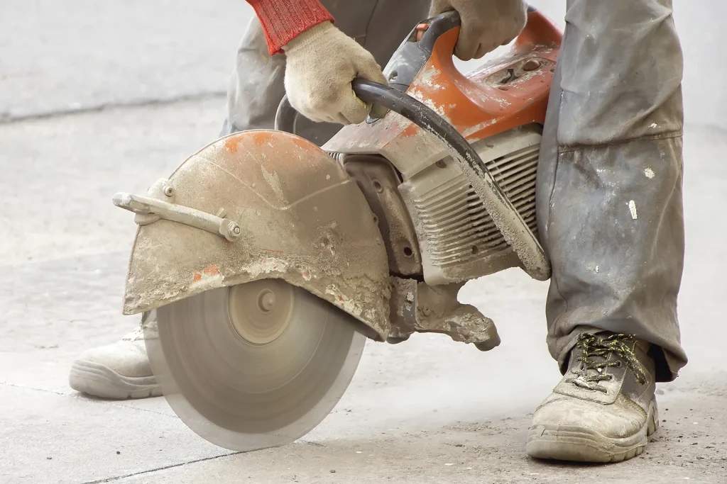 Construction worker using concrete cut-off saw.